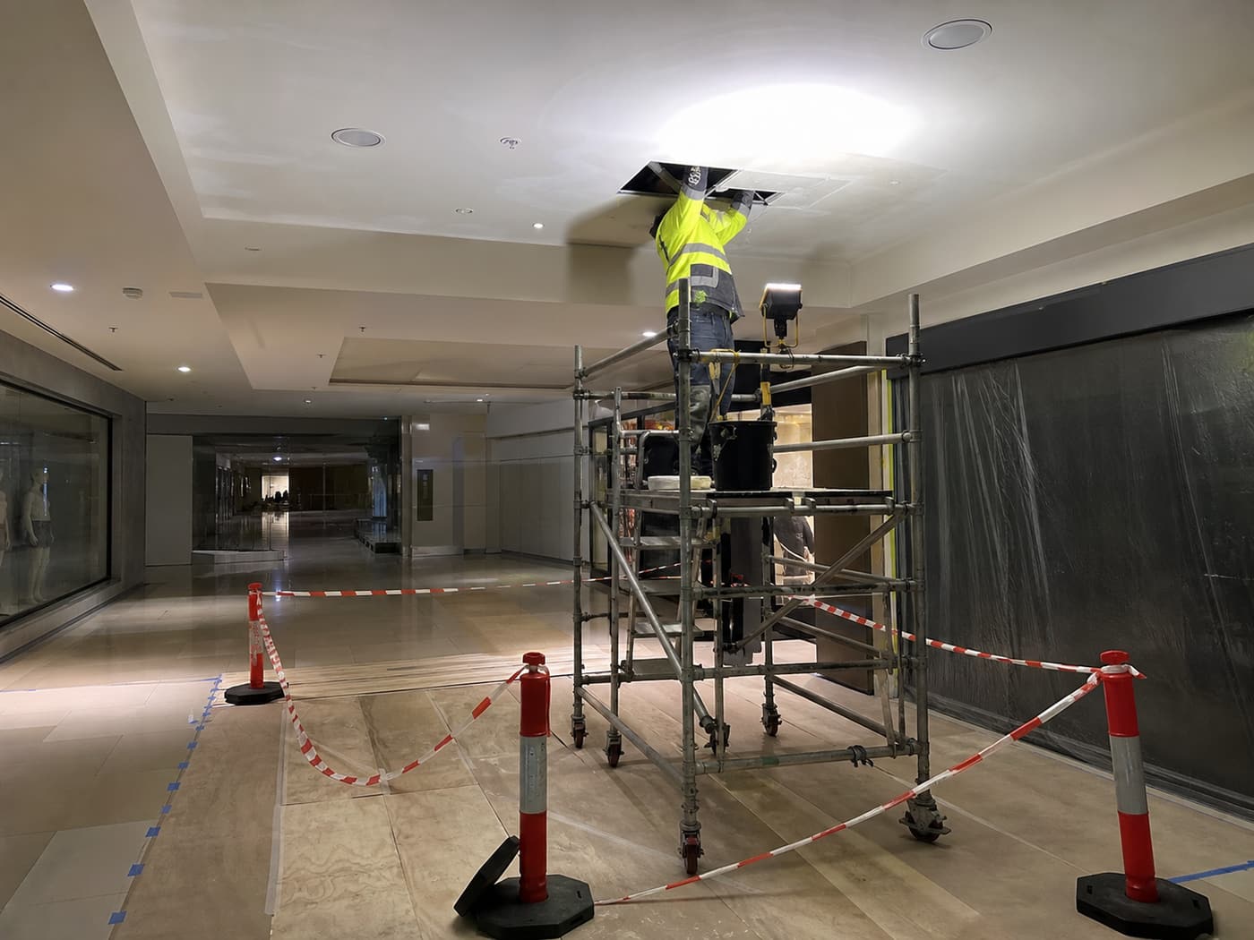 Ceiling repair and repainting in progress above a mall walkway.