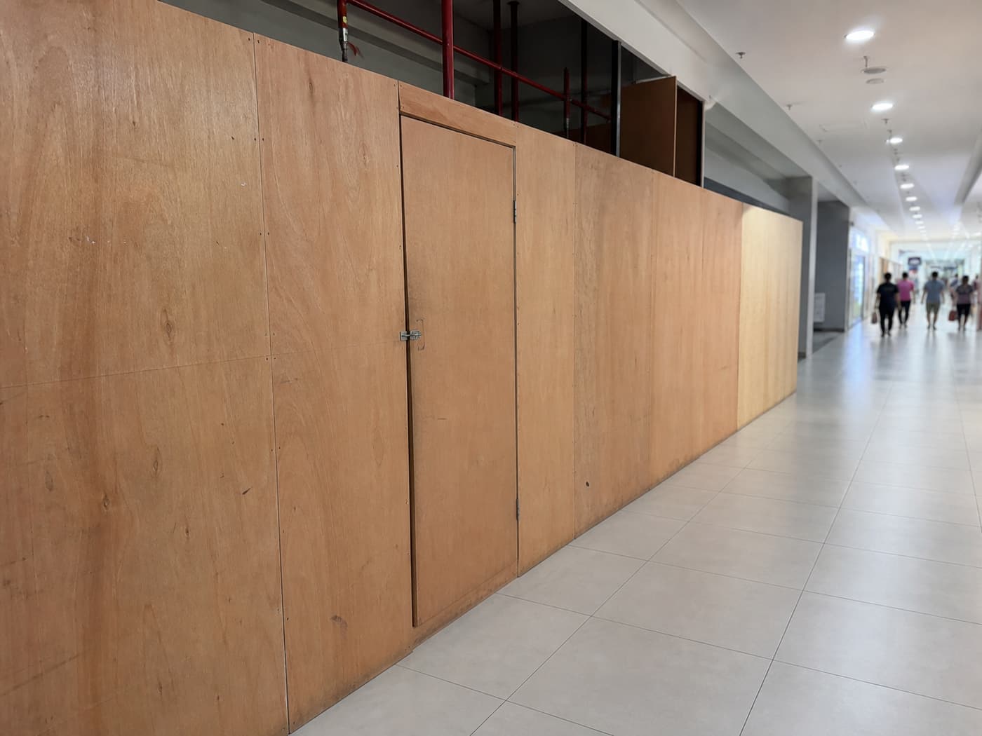 Hoarding boards enclosing a work area in a mall corridor during trading hours.