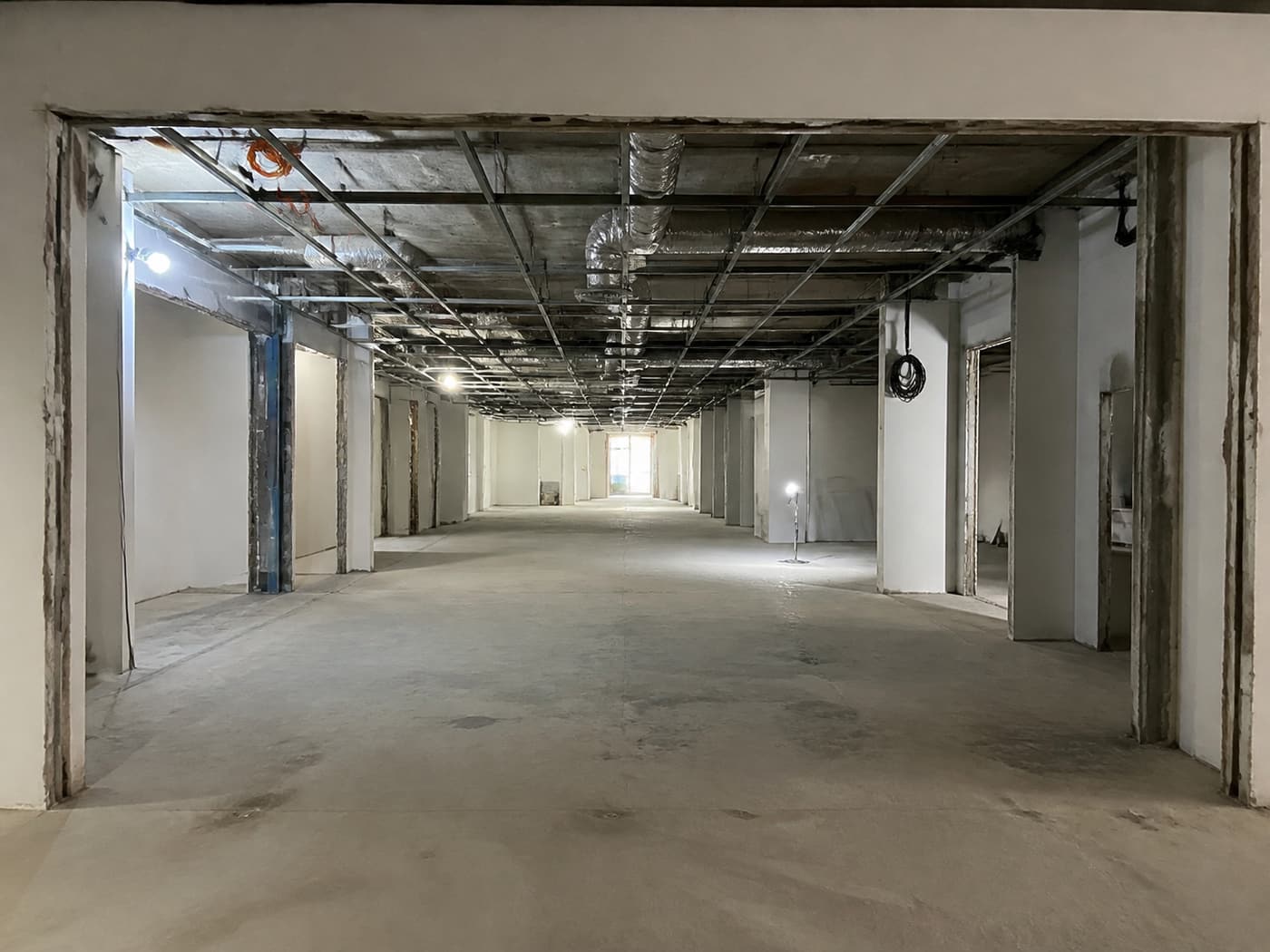 A retail lot stripped back to bare condition, ceiling grid and services exposed.